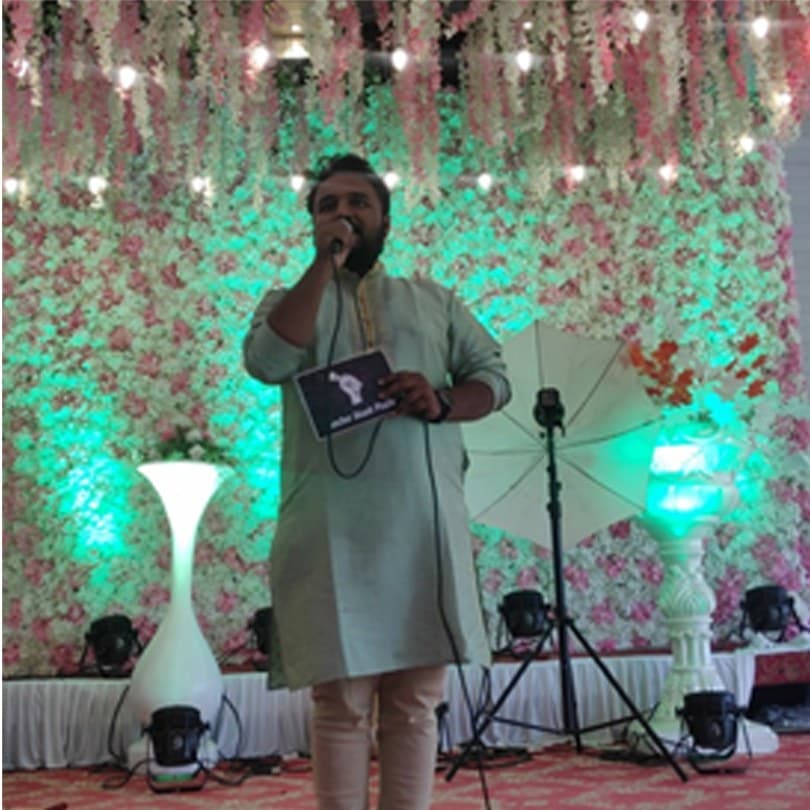 Anchor Akash Phalle hosting a wedding function on a decorated floral stage